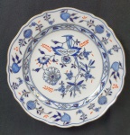 Meissen - Prato em porcelana alemã, da manufatura de Meissen, esmaltado na cor azul, decorado com fios de ouro, sobre fundo branco, do padrão dito Cebolinha e bordas onduladas. Medindo: 3,5 x 24 cm.