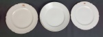 Três pratos em porcelana Breul à Paris, século XIX, brasonado, na cor branca com fio de ouro. Medindo: 23 cm. Apresenta desgastes.