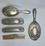 Belíssimo Conjunto para toilette em metal espessurado à prata, ricamente cinzelado, composto de espelho bisotê, 3 escovas e um pente em marfim. Medindo: 27 x 11,5 cm, 23 x 7 cm, 17 x 4,5 cm, 17 x 3,5 cm e 18,5 x 4 cm.