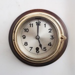 Relógio de navio, alemão. Caixa em bronze sobre base de madeira, vidro bisotado. Não possui chave. Medindo: 18 cm. Não funciona.