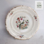 KPM - Prato decorativo em porcelana com delicada decoração flora le pavão ao centro, bordas fileta a ouro. Medindo: 27 cm.