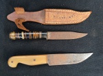 Duas facas pequenas, uma acompanha bainha de couro. Medindo: 12 cm. Apresenta pontos de oxidação.