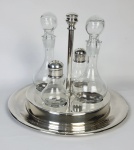 Wolff - Galheteiro em metal espessurado a prata. Medindo: 16 cm, 10 x 15 x 22,5 cm. Recipiente de vidro apresenta fungos e 1 bicado.