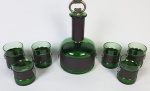 Rústico conjunto para bebidas destiladas composto de garrafa em vidro verde circundado por tira de couro com dois medalhões cara de leão e pega em metal envelhecido com 06 copos do mesmo padrão. Medindo: 26 x 13 cm e 8 x 6 cm.