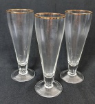 Três tulipas de cristal para cerveja com bordas filetadas a ouro e corpo com efeito canelado. Medindo: 20 x 6 cm.