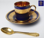 Limoges - França - Xícara de coleção em porcelana francesa na cor azul cobalto com faixas e frisos à folha de ouro decoradas com volutas e arabescos, parte interna da xícara revestida a folha de ouro, marca da manufatura na base, acompanha colher em metal dourado, colher Medindo: 9 cm.