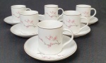 SCHMIDT, Conjunto anos 50, com seis xícaras de café acompanhada de seus respectivos pires, em porcelana esmaltada e vitrificada, delicadamente adornada com ramos florais e bordas com frisos prateados. SEM USO.