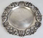 Salva em metal espessurado à prata, com bordas ricamente cinzeladas e pés tripóides. Medindo: