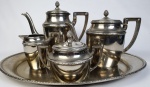 Serviço para chá e café em metal espessurado à prata, com pegas da tampa no feitio de pinha e bordas cinzelada, sendo bandeja (45 x 31), bule para chá (18 x 25), bule para café ( 22 x 25), leiteira (11 x 12) e açucareiro (11 x 12).