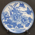 Prato em porcelana chinesa, esmaltado com flores e borboletas em azul, sobre fundo branco. Medindo: 15 cm