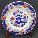 Prato em porcelana na cor branca, esmaltado com flores, detalhes dourados e azul. Medindo: 22 cm. Apresenta degastes na douração.