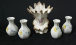 Quatro vasos e uma floreira em porcelana nacional, decoração floral e douração. Medindoi:7 x 4 cm e 13 x 11 x 6,5 cm. Floreira apresenta bicado.