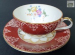 Schmidt - Xícara para chá em porcelana, com faixa na cor vinho decorada com flores e volutas e realces a folha de ouro, parte interna da xícara e fundo do pires com decoração floral policromada. Medindo: 5x11 cm.