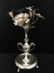 PRATA - Paliteiro em prata brasileira século XIX, em feitio de vaso de flores contendo flores bem feitas e bem elaboradas. Base sobre quatro pés em garras. Peso aproximado: 275 g. Medindo: 21 cm.