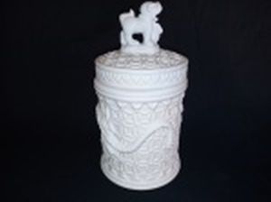 Pote com tampa em biscuit branco, decoração ao gosto chinês com dragão em alto relevo. Pega com cão de Fó. Alt. 18cm.