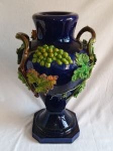 Vaso balaústre, cerâmica vitrificada em azul cobalto, aplicada com cachos de uvas e folhas de parreira coloridos ao natural em alto relevo, alças na forma de galhos. Craquelados na tinta da base, algumas perdas nas folhas. Alt. 47cm.