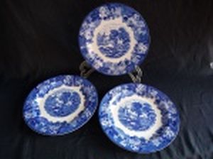 ENOCH WOODS - Três pratos rasos em faiança inglesa azul e branca, decoração moinho, borda com flores e folhas. Marcada no fundo Woods & Sons, England. Um com lascado na parte debaixo da borda. Diam. 23cm.