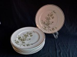 Seis pratos rasos, porcelana nacional decorada com flores e folhas, borda com friso dourado. Marca da Manufatura Schmidt. Diam. 25cm.