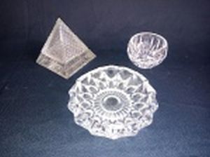 Três peças : a) Caixinha em vidro moldada em forma de pirâmide. Alt. 9 x 8 x 8cm. b) Cinzeiro em demi-cristal francês moldado com estrelados. Diâm. 11cm. c)  Bowl em cristal moldado com caneluras. 5 x 6cm.