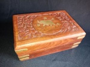 Caixa porta-joias em madeira ao gosto indiano, tampa decorada com flores entalhadas e aplicada com figura de elefante em metal, interior em veludo. 6 x 15 x 10cm