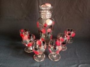 Licoreira e 6 taças, vidro liso decorado com bolas em vermelho, preto, prata e dourado (algumas com desgastes) e frisos prateados. Alt. da garrafa 22cm e taças 8cm.