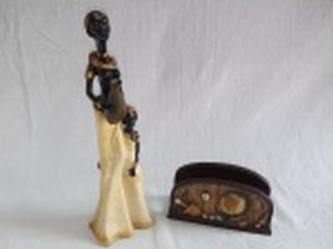 Duas peças: a) Estatueta em resina policromada representando 2 africanas. Alt. 26cm. b) Porta guardanapo em resina decorada com globo terrestre. Comp. 13cm.