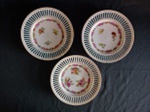 UNION K, Czechoslovakia - Três pratinhos decorativos em porcelana tcheca branca, borda filetada a ouro com vazados em sulcos, decoração com cinturão e arranjos florais. Leves perdas na douração. Marcada no fundo. Primeira metade do século XX. Diâm. 16cm.