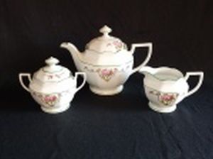SCHMIDT - Três peças para serviço de café em porcelana nacional branca: bule, açucareiro e leiteira. Decoração com arranjos florais lilás e frisos verdes. Apresenta leves craquelados na tampa do açucareiro. Marcados no fundo. Alts. 18, 12 e 9cm.