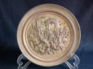 Placa decorativa redonda em metal aplicada no centro em alto relevo com cena da queda do Império Romano, representando o ataque dos visigodos às portas do Senado. Diâm. 22cm.