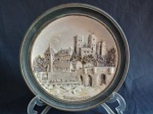 Placa redonda em cerâmica verde e branca decorada no centro com a figura do Castelo de Kreutzenstein, na Baixa Áustria. Diâm. 22cm.