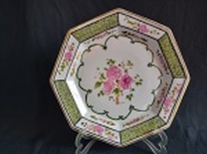 Prato em porcelana branca, formato oitavado, borda e detalhes filetados a ouro, pintado à mão com folhagens e crisântemos. Assinado, Sandra. Diâm. 32cm.