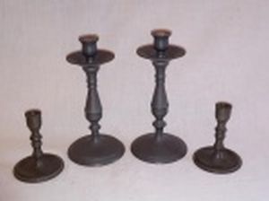 Dois pares de castiçais em estanho, base redonda e haste em balaústre. O menor marcado LIARTE. Alts. 7,5 e 15cm.