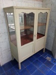 Vitrine em madeira brasileira pintada de cinza, 2 portas emoldurando vidro (falta 1 vidro), interior com 2 prateleiras, tampo e ilhargas com tremidos. Década de 40. 127 x 97 x 40cm.