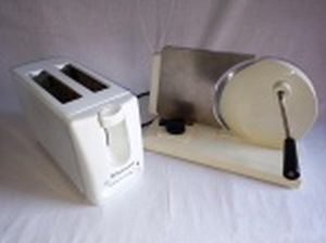 Duas peças: a) Torradeira elétrica Toastmaster. 17 x 27 x 11cm. b) Fatiador de frios manual. Manufatura Eberle. 20 x 30 x 20cm.