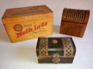 Três caixas em madeira: a) Formato retangular aplicada com guarnições de metal amarelo. 6 x 9 x 5,5cm. b) Formato de baú decorada com ranhuras. 9,5 x 9 x 7,5cm. c) Retangular do "Matte Leão". 10 x 16 x 10cm.