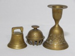Três sinetas em metal amarelo indiano, diferentes formas, uma acimada por porta-velas formando castiçal. Alts. 10 e 5cm.