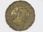 Medalhão em bronze ricamente decorado em alto relevo com anjos e folhagens na borda, centro apresentando cena com figuras místicas em taverna. Diâm. 21cm.