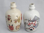 Duas garrafas para saquê em cerâmica vitrificada decoradas com motivos japoneses, uma com máscara e caracteres kanji; e uma com figuras de brinquedos japoneses. Alt. 19cm.