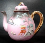 MADE IN JAPAN - Bule para chá em porcelana japonesa `Casca de Ovo` de tons rosa/marrom com pintura em ouro na alça e na pega da tampa além de decoração de paisagem oriental em alto relevo. Mede 19,5 cm de altura por 17,5 cm da alça ao bico.