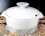 PORCELANA RENNER MEDAILLON - Grande sopeira em porcelana branca decorada por faixas em tons sutis de cores ditas `bebê` na base da sopeira e na pega da tampa. Mede 16 cm de altura por 25 cm de uma alça a outra.