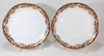 MON CHÉRI RENNER - Belo par de pratos dito rasos em porcelana branca ricamente decorada por faixa de tom avelã sob flores e ramagens douradas, além de filetação em ouro na borda. Medem 25 cm de diâmetro cada.