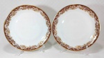 MON CHÉRI RENNER - Belo par de pratos dito rasos em porcelana branca ricamente decorada por faixa de tom avelã sob flores e ramagens douradas, além de filetação em ouro na borda. Medem 25 cm de diâmetro cada.