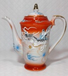 Magnifico bule para café em porcelana oriental de tons branco e `rouge de fér` ricamente decorado por figuras de dragões em alto relevo e filetação dourada. Mede 19,5 cm de altura por 18 cm da alça ao bico.