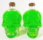 Decorativo par de garrafas em vidro no formato de crânios com tampa em rolha de cortiça decorados por anilina verde limão. Medem 15 cm de altura por 12 cm de compriemento e 7,5 cm de largura cada. 