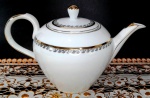 PORCELANA STEATITA - Grande bule para chá em porcelana branca com pintura em ouro na alça, no bico e na pega da tampa além de arabescos em tom prata. Mede 16 cm de altura por 23 cm da alça ao bico.