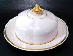 PORCELANA REAL - Manteigueira em porcelana de tom rosa bebê com pintura em ouro na pega da tampa e ao redor da borda (possui desgaste na borda) medindo 8 cm de altura 14,5 cm de diâmetro.