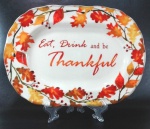 Grande e pesada travessa ivory com decoração de folhagens e frutos em policromia com os dizeres ` Eat, drink and be thankful` no centro. Mede 25 cm de largura por 35 cm de comprimento. 
