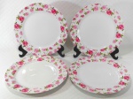 Lote contendo 4 grandes pratos rasos de pesada porcelana branca ricamente decorada por larga faixa de rosas em policromia. Medem 27 cm de diâmetro cada.