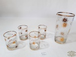 Lote de 5 peças sendo 4 copos de aperitivo e 1 licoreira decorados com ouro. Medida menor 5 cm diâmetro, 7,5 cm altura, maior 8 cm diâmetro, 15,5 cm altura.