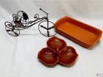 Lote composto de travessa retangular em cerâmica refratária, petisqueira na forma de folha em porcelana marrom e descanso de garrafa na forma de triciclo. Medindo a travessa 31cm x 18,5cm x 5,5cm de altura.